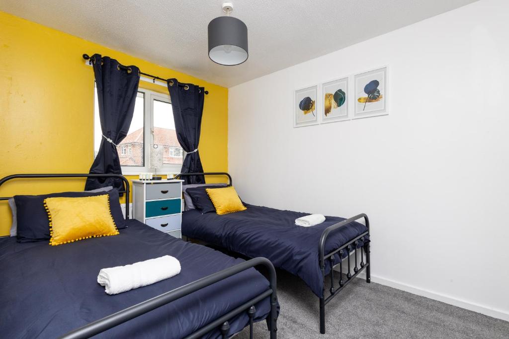 two beds in a room with yellow walls at Gorgeous Grange Fields Home - Free Parking, Self Check-in, High Speed Wi-fi, Excellent City Centre Access - Contractors Welcome in Leeds