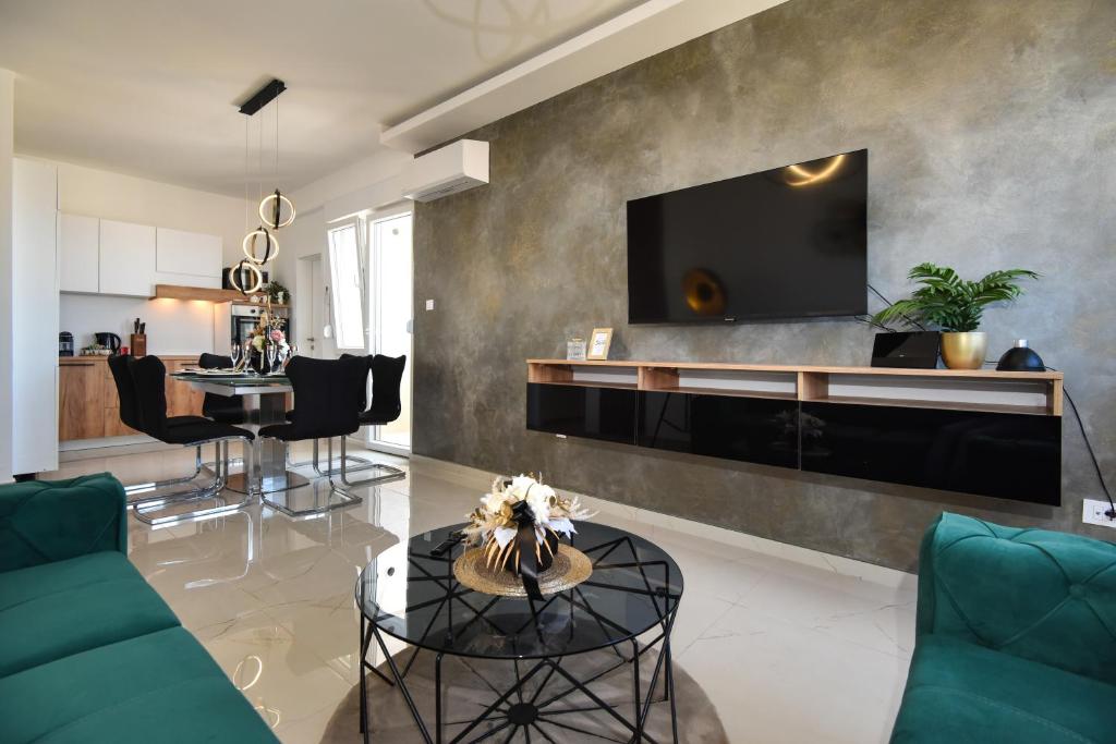 a living room with a couch and a tv on a wall at Apartman Nella with sea wiew in Zadar