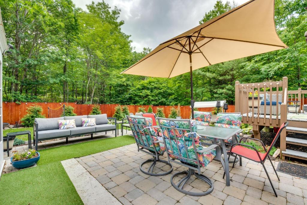 a patio with a table and chairs and an umbrella at Pocono Summit Home with Game Room, 3 Mi to Kalahari! in Pocono Summit