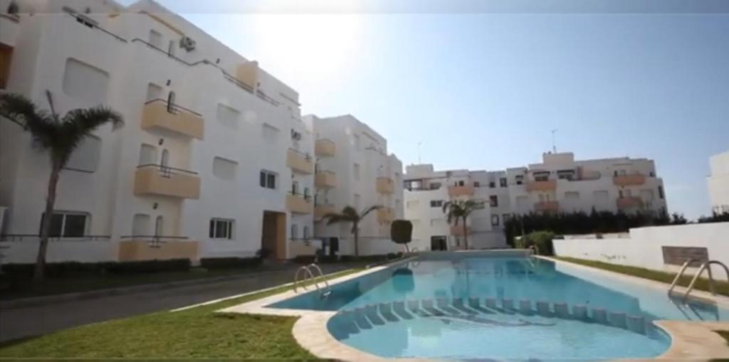 a swimming pool in front of a building at Appartement avec piscines, vue sur mer et accès à la plage à Achakar Hill, Tanger. in Tangier