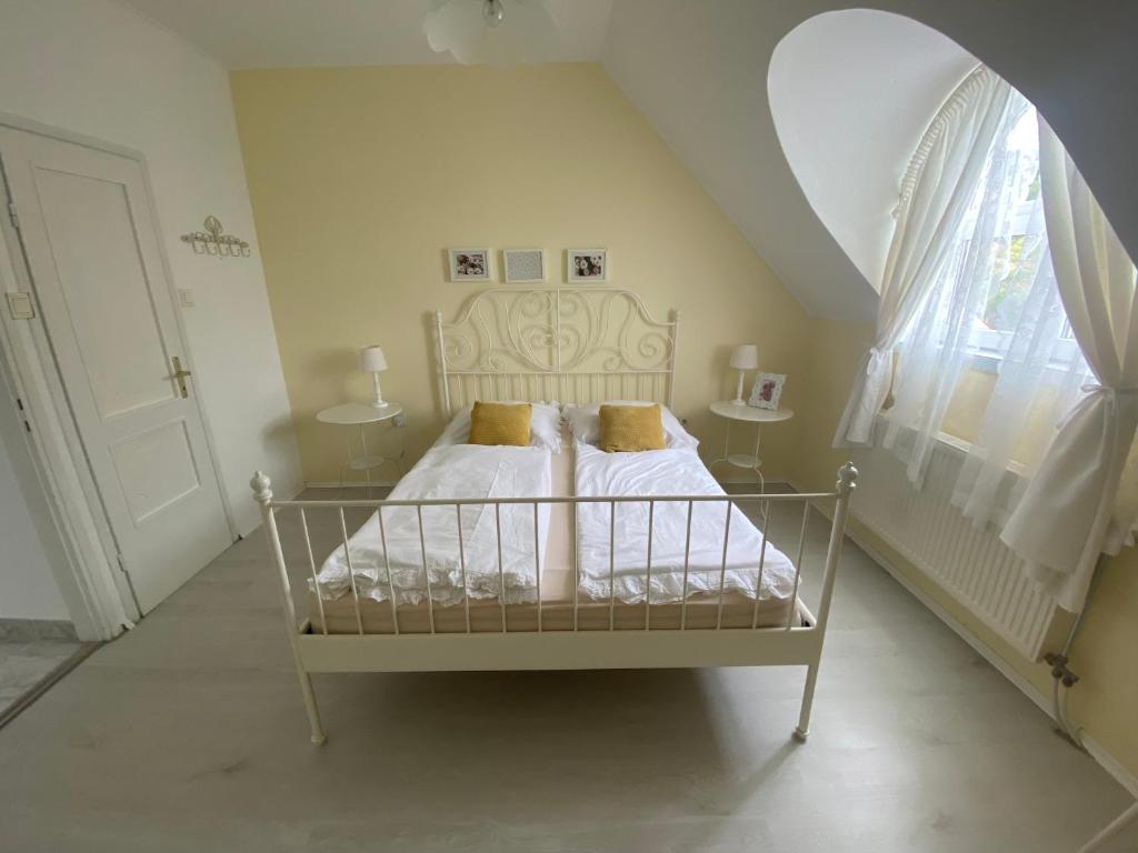 ein weißes Bett in einem Zimmer mit Fenster in der Unterkunft Vázsonyi vendégház in Balatonfüred