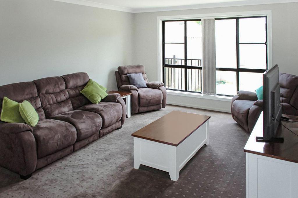 een woonkamer met een bank, 2 stoelen en een tv bij Quintet 1 157 in Tamworth