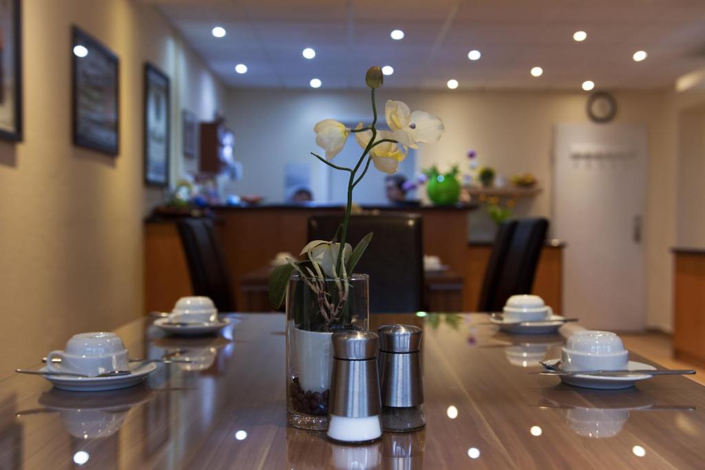 una mesa con un jarrón con flores. en Hotel Eckstein en Berlín