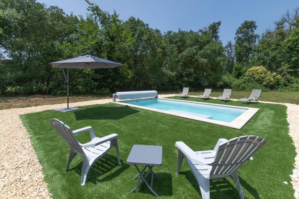 - une piscine avec des chaises, un parasol et une table dans l'établissement Villa Graveyron - Maison avec piscine privée, à Berrias Et Casteljau