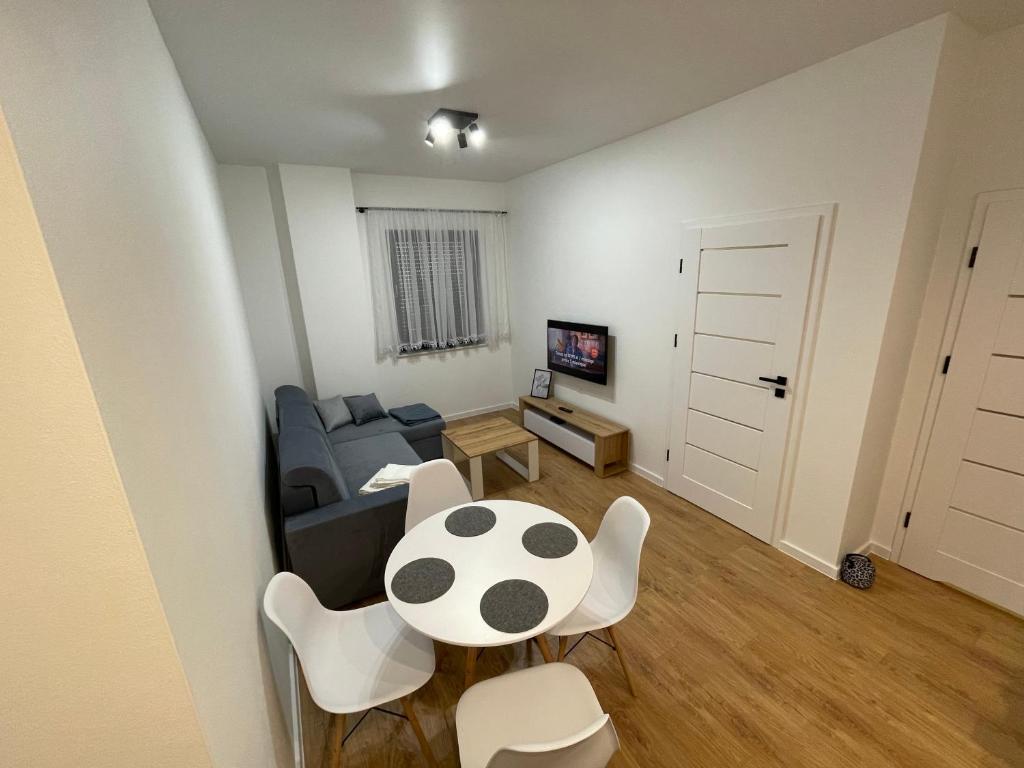 ein Wohnzimmer mit einem Sofa, einem Tisch und Stühlen in der Unterkunft Apartamenty Lipowy Zakątek in Iława