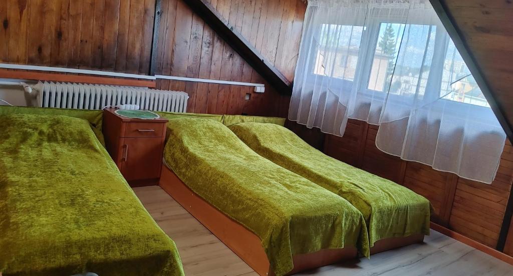 a bedroom with two beds with green covers and a window at Suwałki Centrum Studio in Suwałki