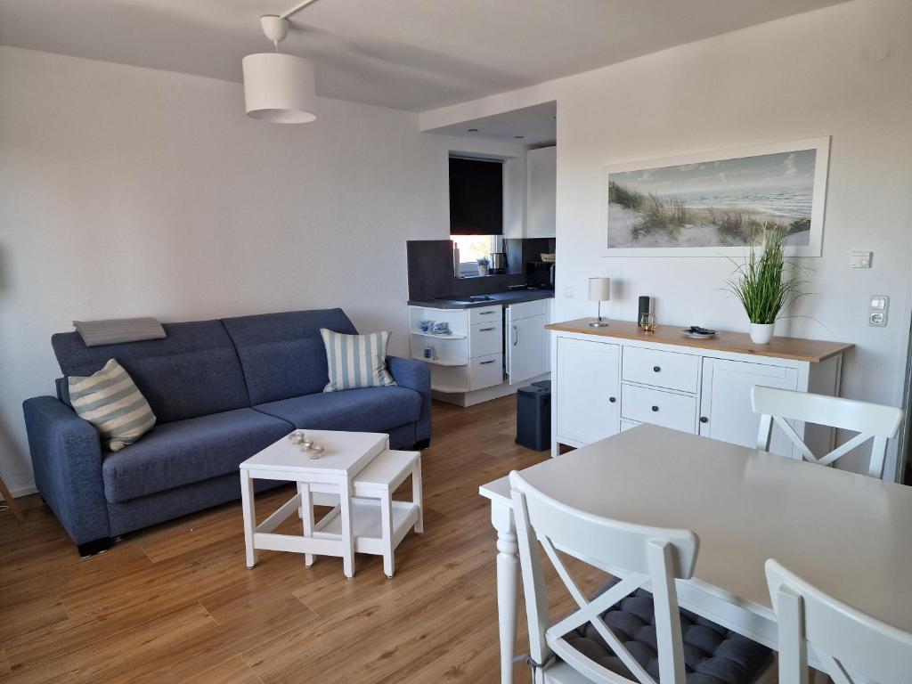 uma sala de estar com um sofá azul e uma mesa em Tief 10 Wohnung 102 Heimathafen em Wangerland