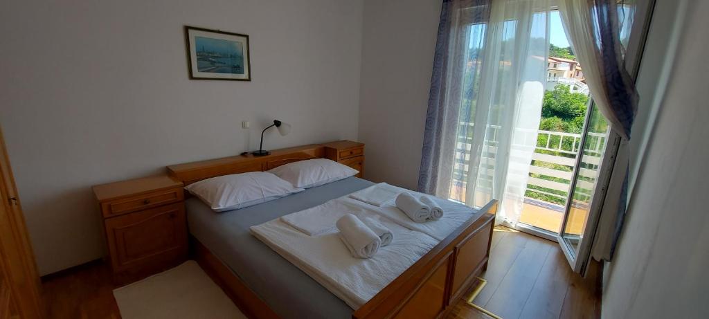 a bedroom with a bed with white sheets and a window at Apartman Franelić Banjol in Banjol