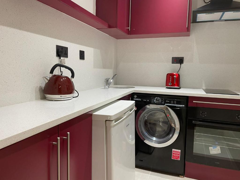 a kitchen with a washing machine and a tea kettle at King Studio Apartment with Garden and Parking in Ealing