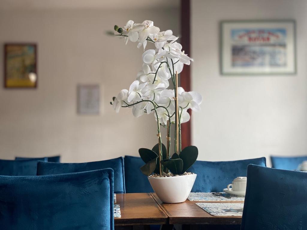 Hotel le Pasteur في رويان: طاولة مع مزهرية مع الزهور البيضاء عليها