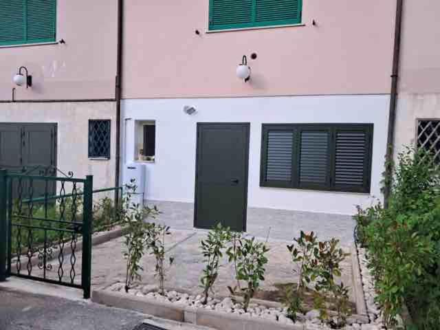 a white building with green windows and a door at “Molise” Four Seasons in San Massimo