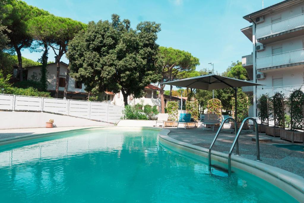 a swimming pool with an umbrella next to a building at Residence Conchiglie in Marina Romea