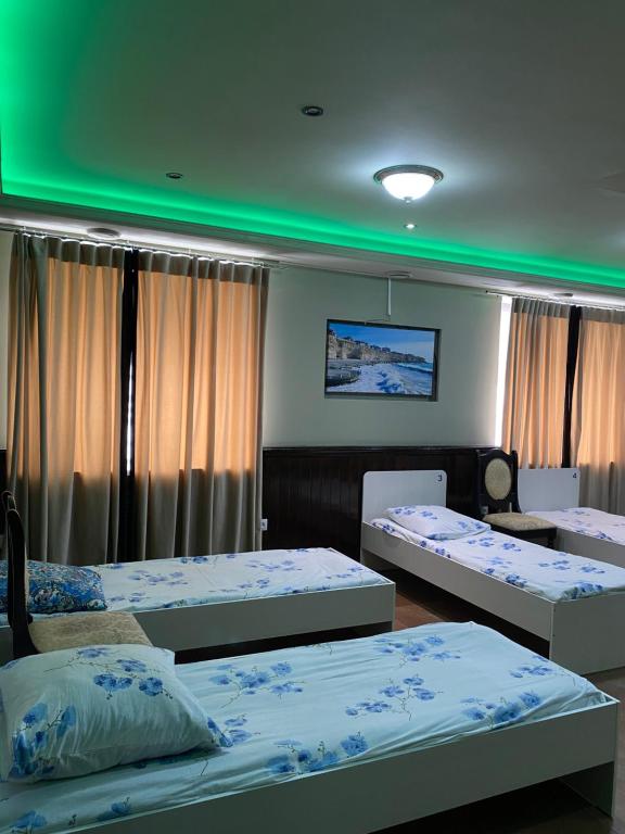 een kamer met drie bedden en een groen plafond bij Mang’o Hostel in Aqtau