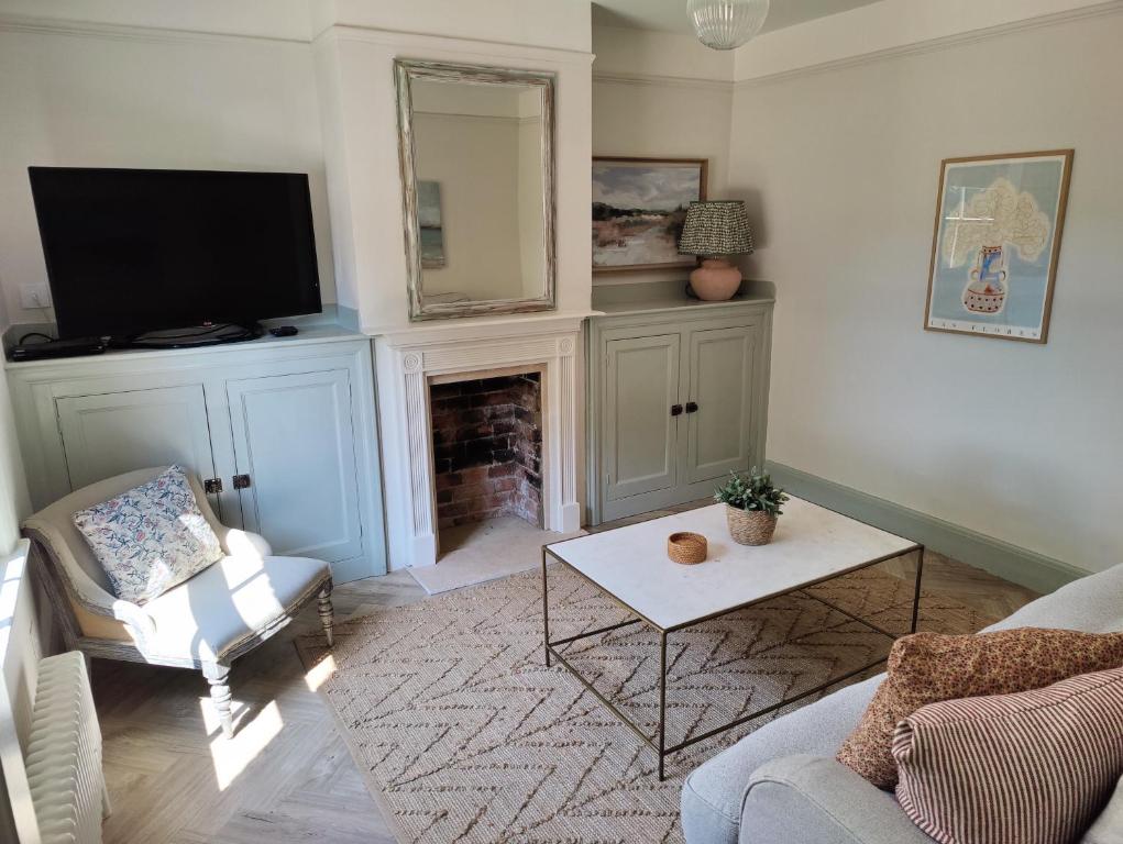 a living room with a tv and a fireplace at Stunning New Forest Cottage close to Paultons Park in Ower