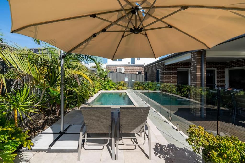a patio with an umbrella and chairs and a pool at Sea Change in Shellharbour