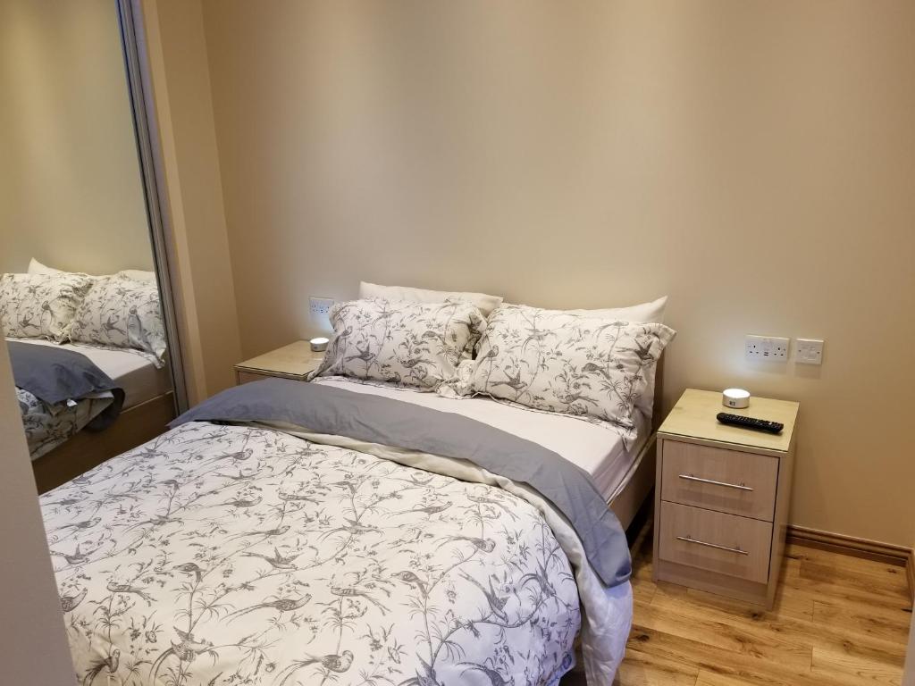 a small bedroom with a bed and a mirror at London Luxury Apartment 4 Bedroom Sleeps 12 people with 4 Bathrooms 1 Min walk from Station in Wanstead
