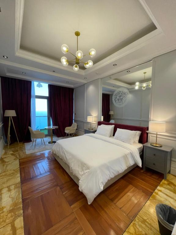 a large bedroom with a large white bed and a chandelier at أجنحة فرزاتشي برج داماك الجوهرة in Jeddah