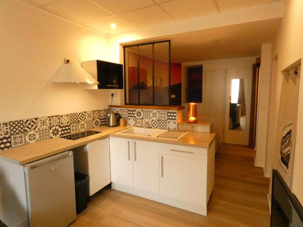 une cuisine avec des placards blancs et un comptoir dans l'établissement Charmant studio lumineux avec Wifi, à La Bourboule