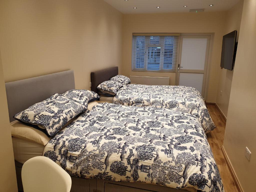 1 dormitorio con 2 camas, ventana y silla en London Luxury Apartments 3 Bedroom Sleeps 8 with 3 Bathrooms 4 mins walk to tube free parking, en Ilford