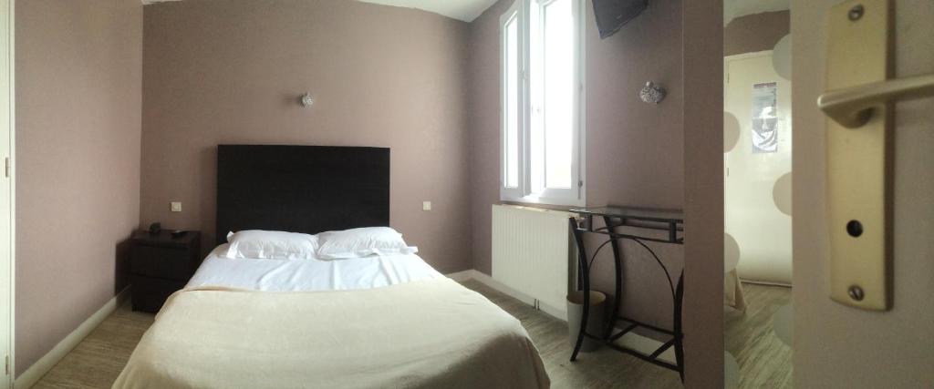 a bedroom with a white bed with a window at Hotel Les Voyageurs in Les Sables-d'Olonne