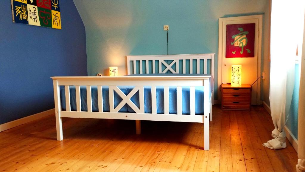 ein weißes Kinderbett in einem Zimmer mit Holzboden in der Unterkunft Gemütliches Privatzimmer in Schömberg