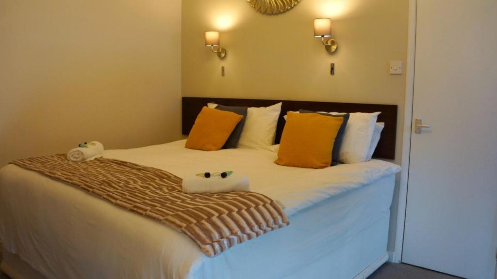 a bedroom with a bed with orange and white pillows at OYO Oban Hotel in Eastbourne