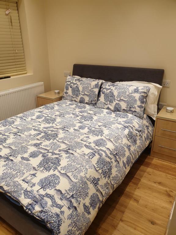 a bedroom with a bed with a blue and white comforter at London Luxury Apartments 3 Bedroom Sleeps 8 with 3 Bathrooms 5 mins Walk to tube station free parking in Ilford