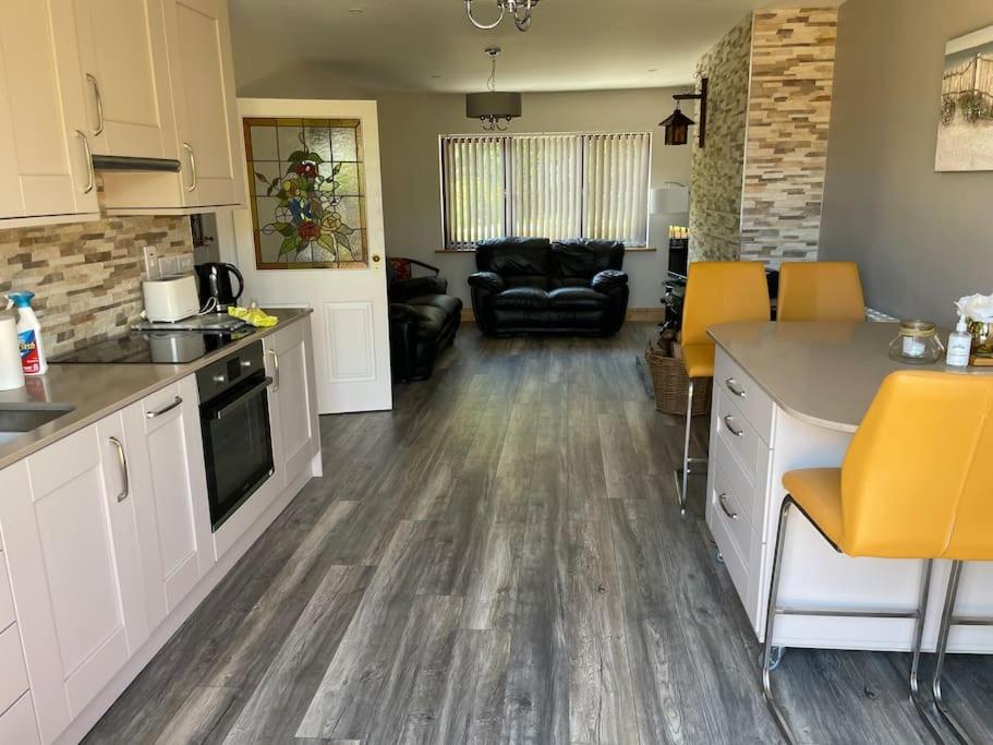 a kitchen and living room with yellow chairs and a table at Harmony House enclosed property near beach and lake in Tramore