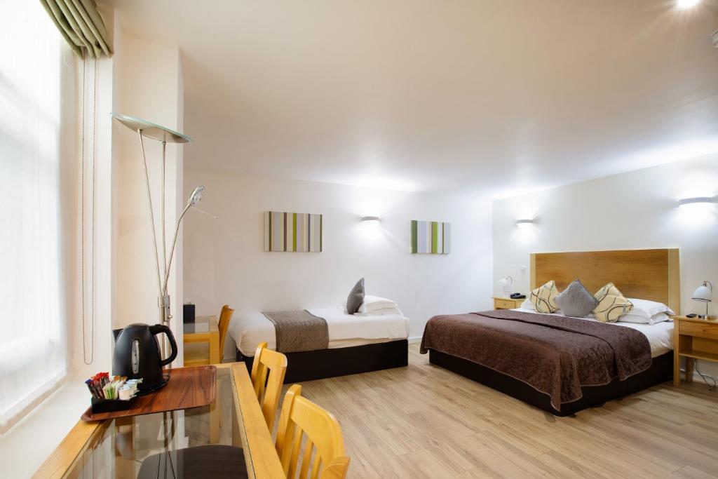 ロンドンにあるザ クリーブランドのベッド2台とテーブルが備わるホテルルームです。