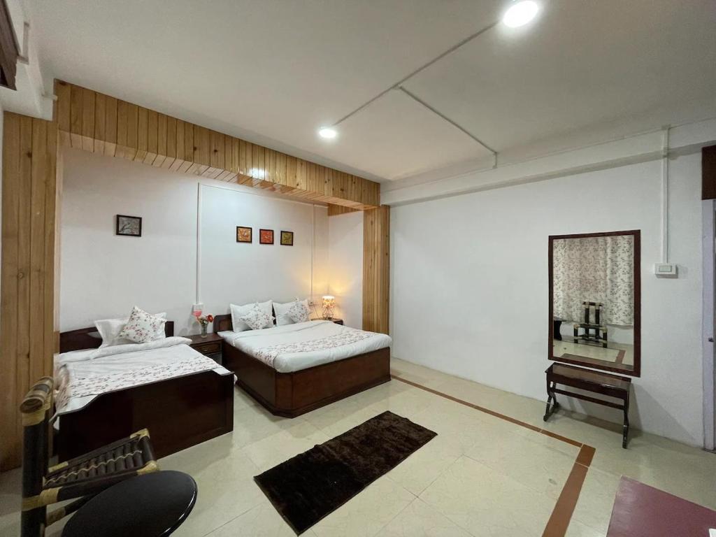 a room with two beds and a chair in it at Monratino Ridge View in Gangtok