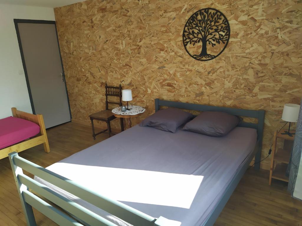 - une chambre avec un lit et un arbre sur le mur dans l'établissement Gîte centre ville de Thiviers, à Thiviers
