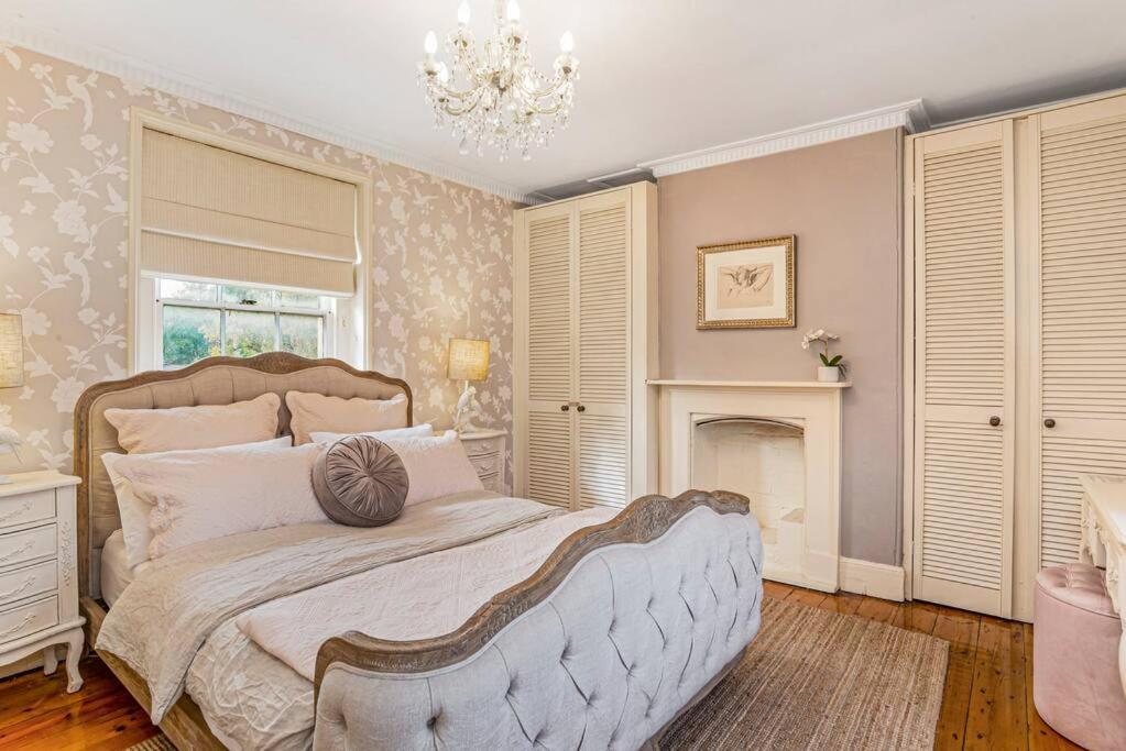 a bedroom with a large bed and a chandelier at Firebird Cottage A Hallmark to Adelaides History in Bowden