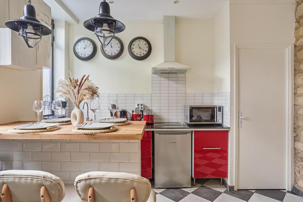 a kitchen with a counter with clocks on the wall at Apartment Center of Paris by Studio prestige in Paris