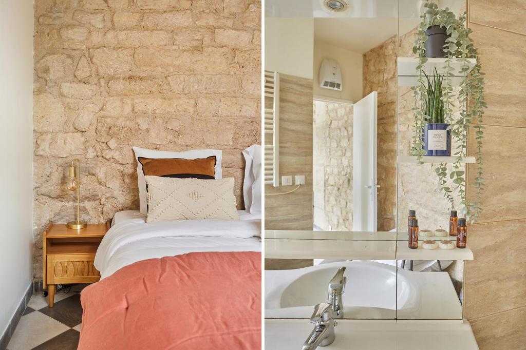 a bedroom with a bed and a sink and a stone wall at Apartment Center of Paris by Studio prestige in Paris