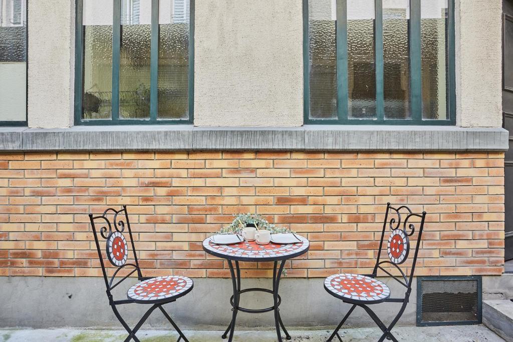 two chairs and a table in front of a brick wall at Apartment Center of Paris by Studio prestige in Paris