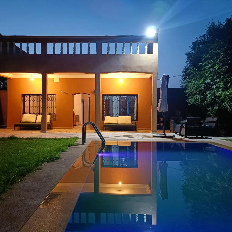 a swimming pool in front of a house at night at Villa Ama in Marrakesh