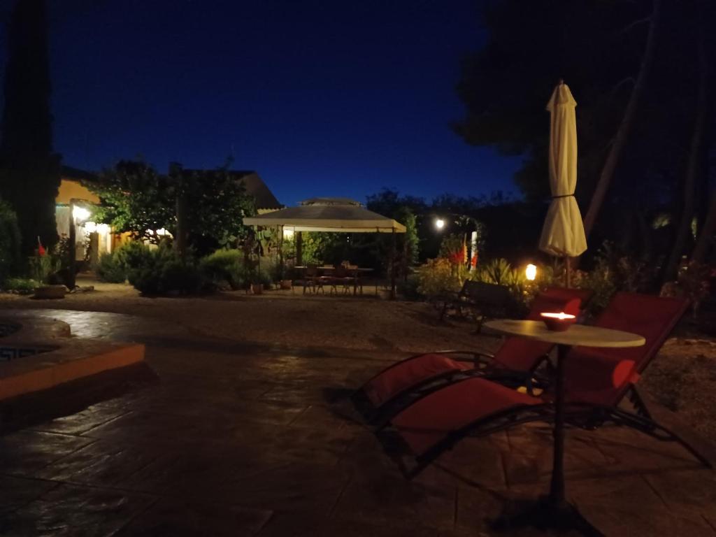 a patio with a table and an umbrella at night at Casa del Riu in Benejama