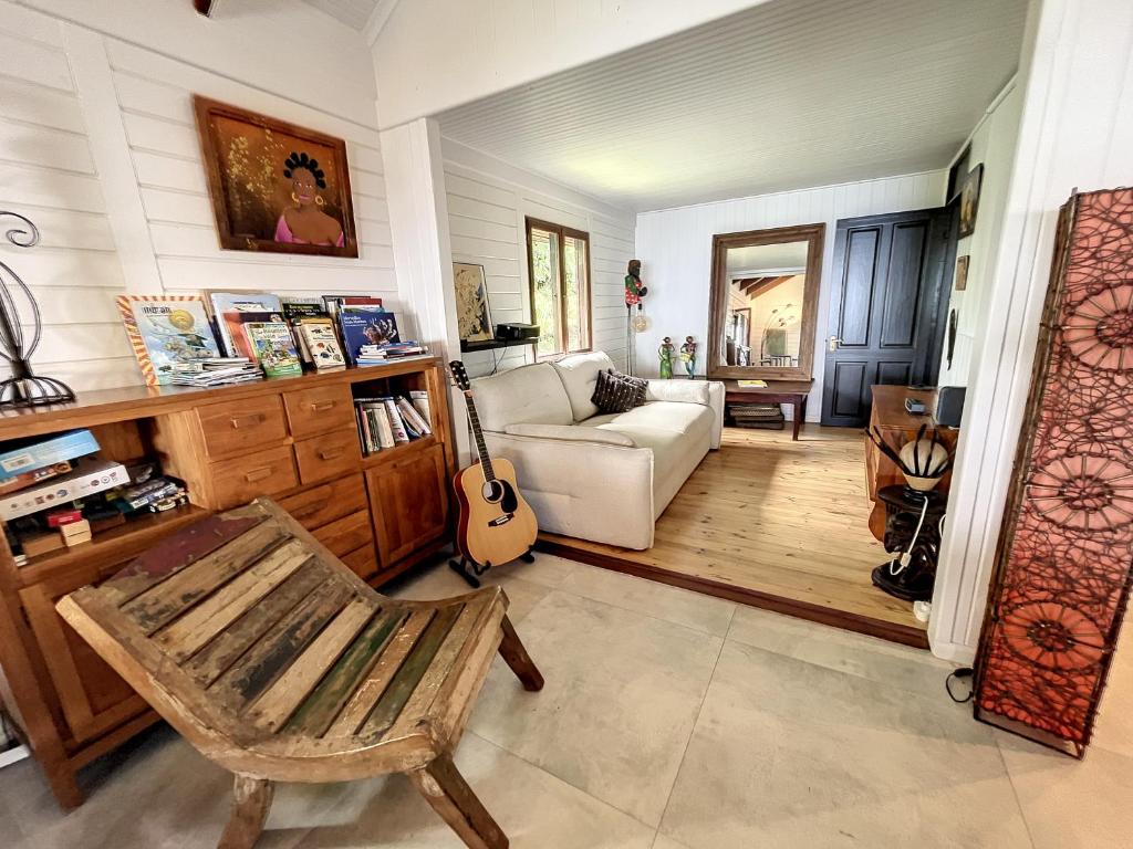 a living room with a chair and a guitar at Maison camomille in Le Cap