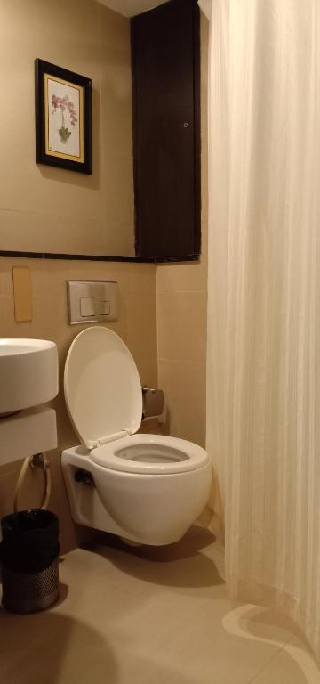 a bathroom with a white toilet and a shower curtain at SVN GRAND in Kākināda