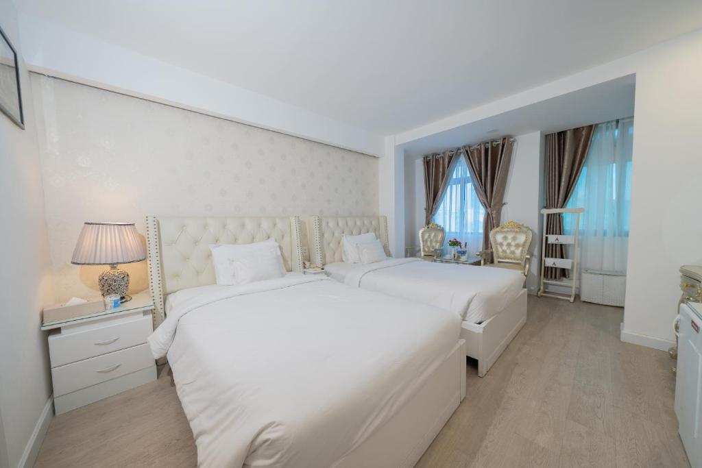 2 bedden in een witte kamer met ramen bij A25 Hotel - 255 Lê Thánh Tôn in Ho Chi Minh-stad
