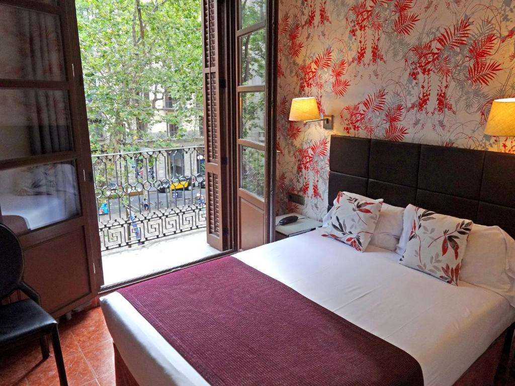 a bedroom with a bed and a large window at Hotel Lloret Ramblas in Barcelona