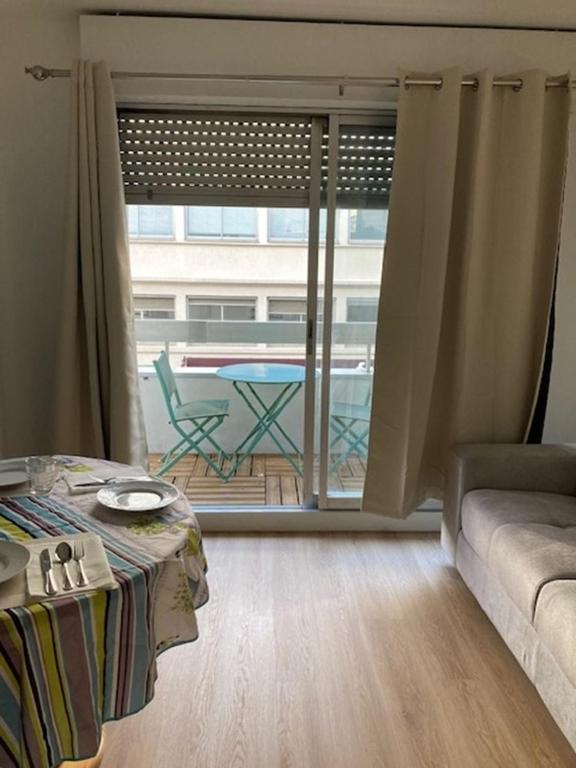 ein Wohnzimmer mit einem Sofa und einem Tisch sowie einem Balkon in der Unterkunft Charmant Studio à Boulogne Nord proche porte d'Auteuil in Boulogne-Billancourt
