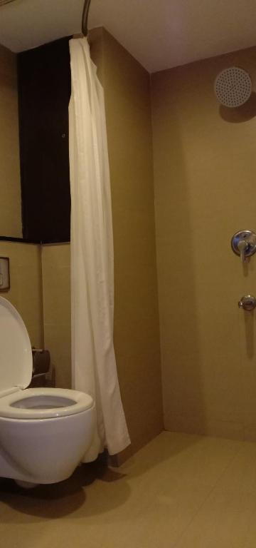a bathroom with a white toilet and a shower at SVN GRAND in Kākināda