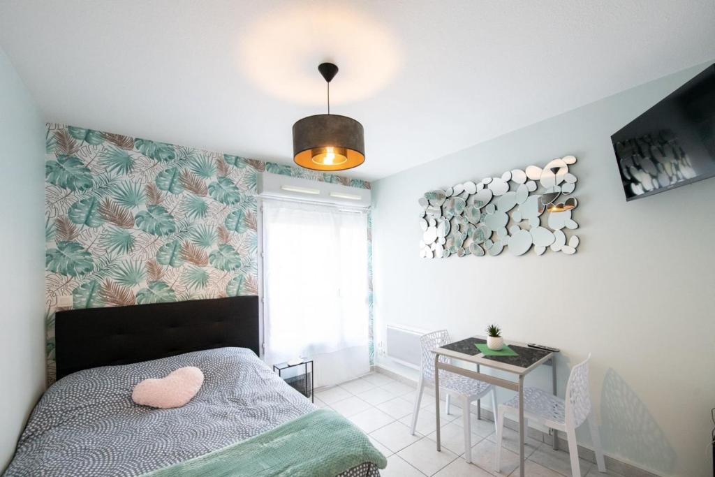 Schlafzimmer mit einem Bett, einem Tisch und einem Fenster in der Unterkunft The Anatole - Cosy & calm apartment in Villeurbanne