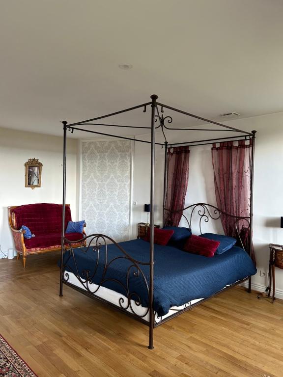 a bedroom with a canopy bed with blue sheets and red pillows at chambre romantique dans le château de la Bouchatte in Chazemais