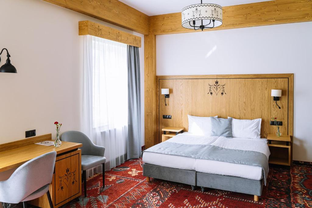 a bedroom with a bed and a desk and a chair at Hotel Maria & Spa in Szczawnica