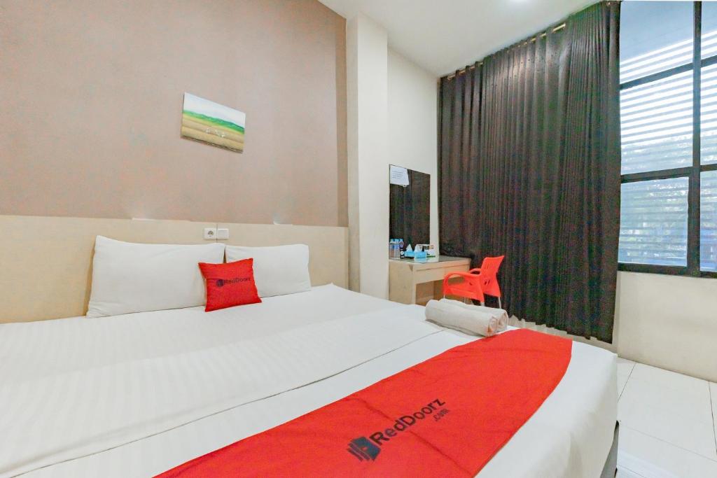 um quarto com uma cama grande e um cobertor vermelho em RedDoorz near Pasar Tarapung Siring Banjarmasin em Banjarmasin