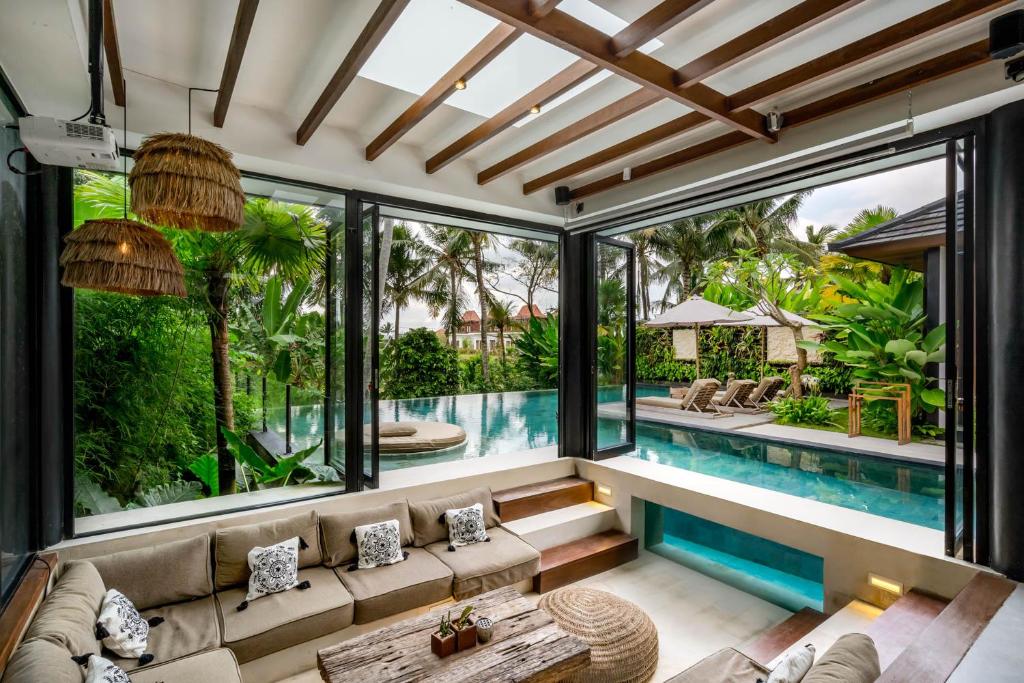 ein Wohnzimmer im Innenbereich mit einem Pool und großen Fenstern in der Unterkunft Villa Fiery by BaliSuperHost in Ubud