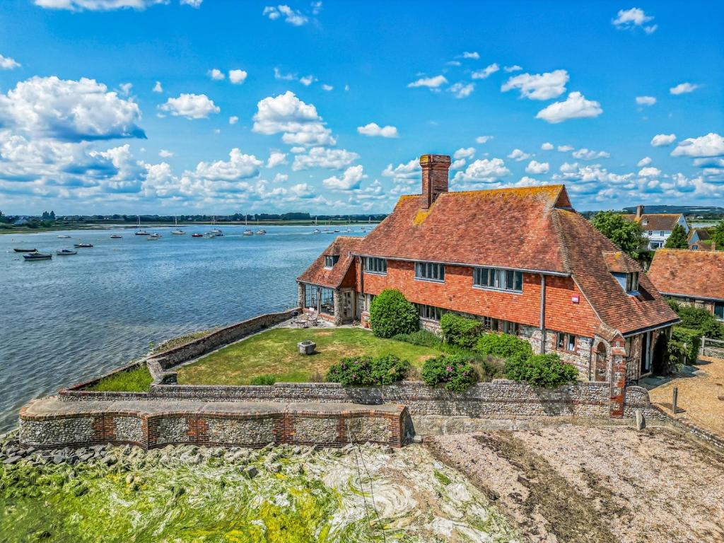an old house on the water with boats in it at Pass the Keys Historic Waterfront Home in Bosham in Bosham