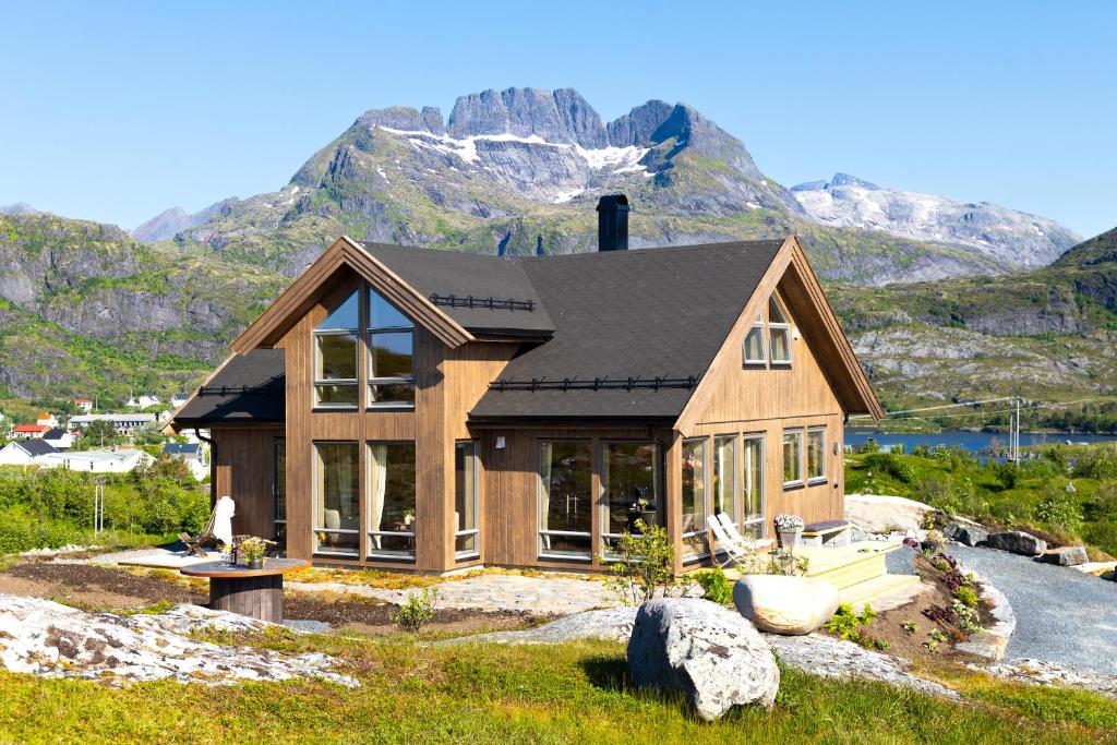 a house on a hill with mountains in the background at The Magic View of Lofoten - Nature & SEA in Sørvågen